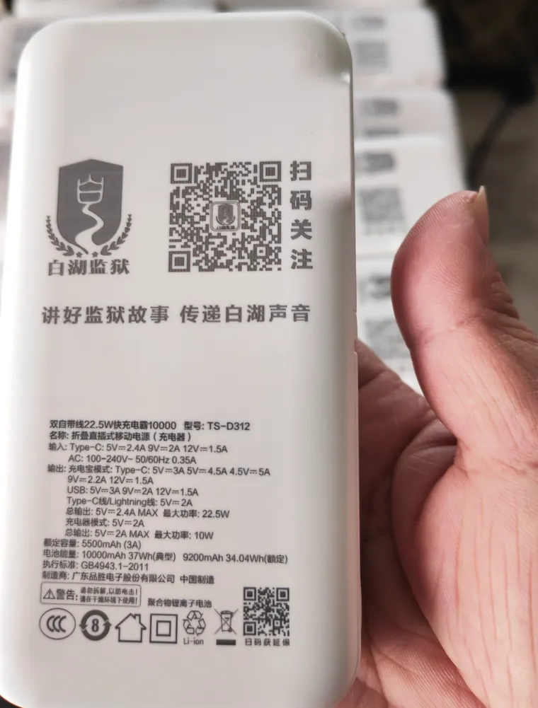 合肥激光打标代工实拍 · 白色移动电源充电宝表面激光打标单位徽标、二维码和「扫码关注」字样，背面参数同批打全，批量出货逐个一致、二维码可扫可识别